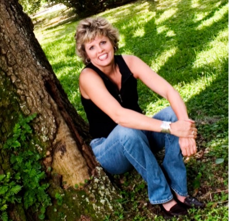 stroke survivor Valerie Greene seating by a tree and smiling 