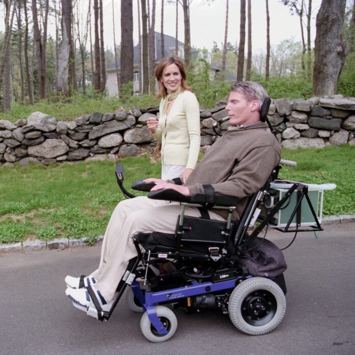Dana Reeve walks beside Christopher Reeve using his wheelchair
