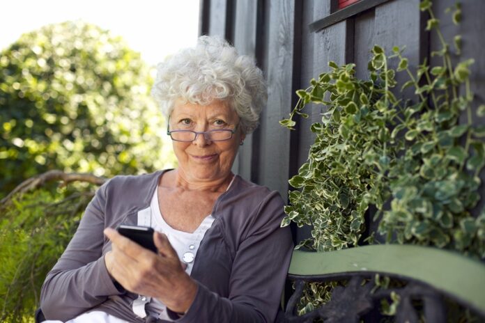 woman wearing reading glasses, holding a cell phone