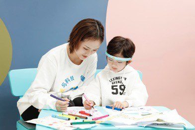 woman seated with child who is wearing a BrainCo headband for autism intervention