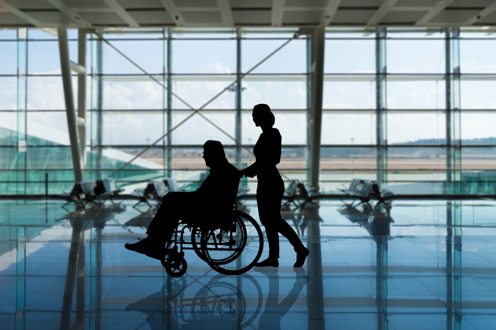 person assisting wheelchair user through airport 