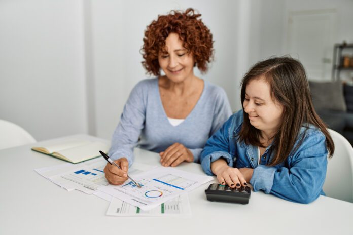 woman seated beside another woman with Down syndrome, working on taxes together