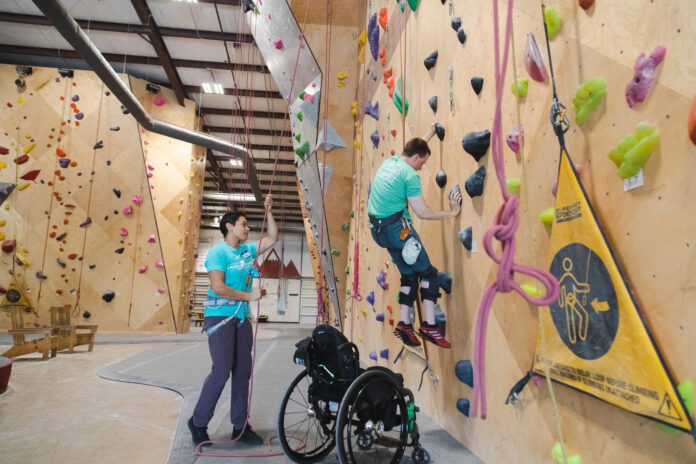 A wheelchair user climbs an adaptive climbing wall