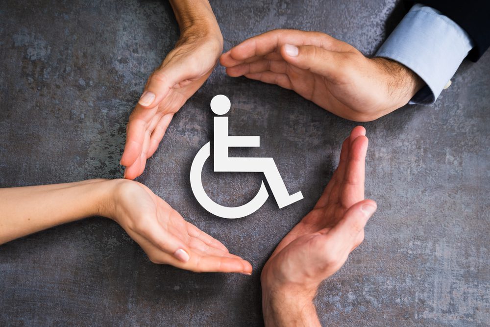 four hands forming a circle around handicapped symbol