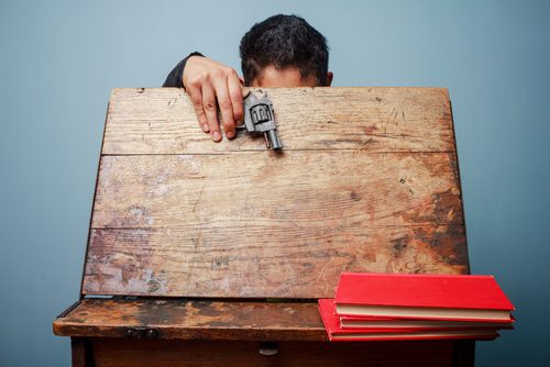 student holding handgun over desk