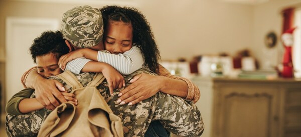 Military parent hugging his two children.
